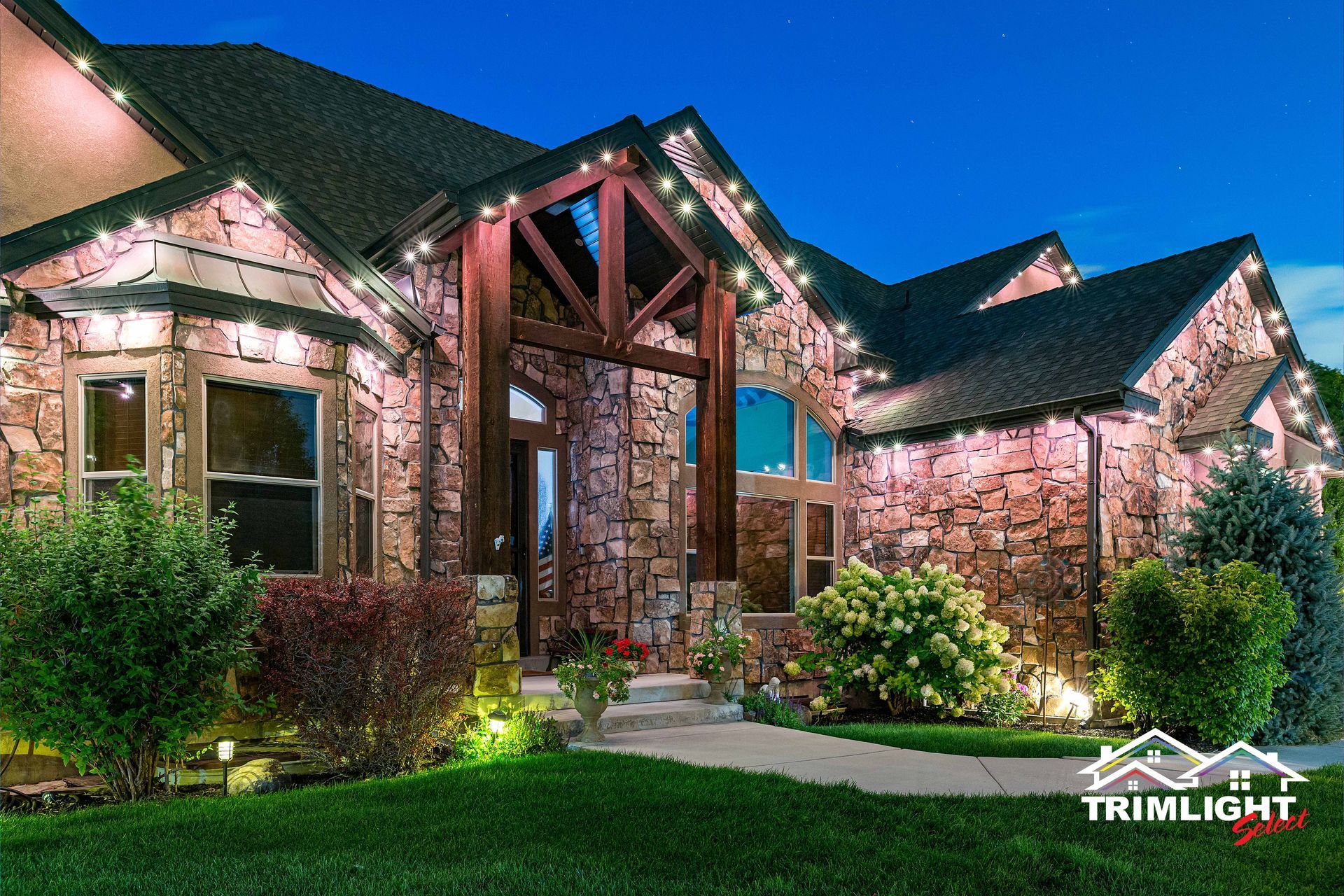 House with stone facade illuminated by Christmas lights at night.