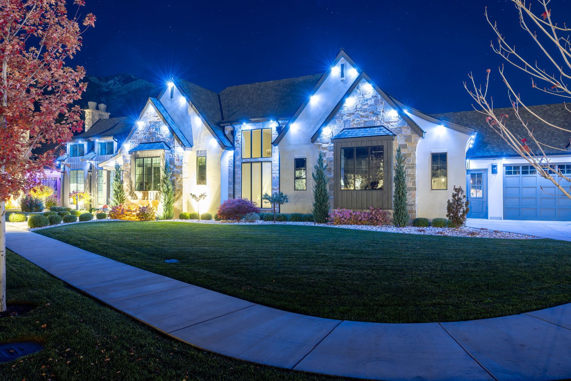 A house lit up with blue Christmas lights on the roof, at night.