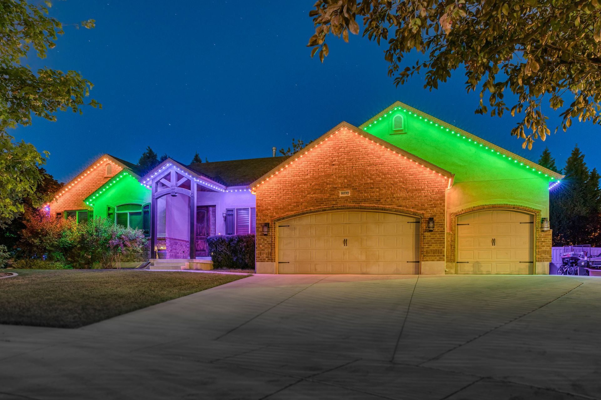 House decorated with green and orange Christmas lights at night.