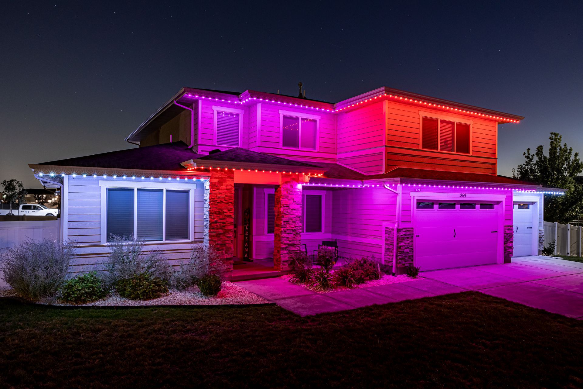 House exterior lit with red, purple, and white lights at night.