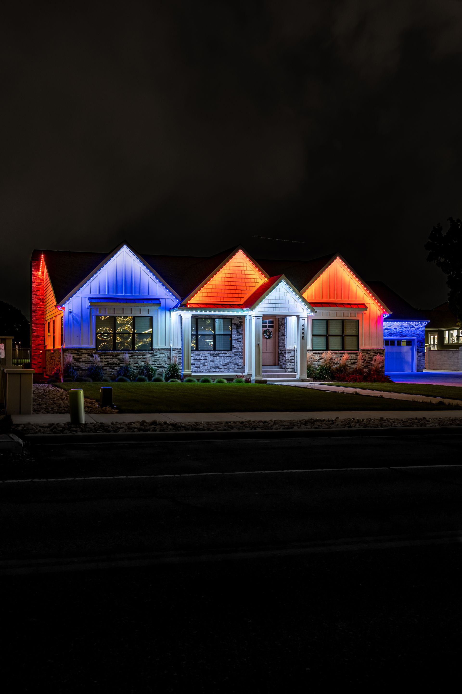House lit with red, white, and blue lights, with a dark sky background, festive.