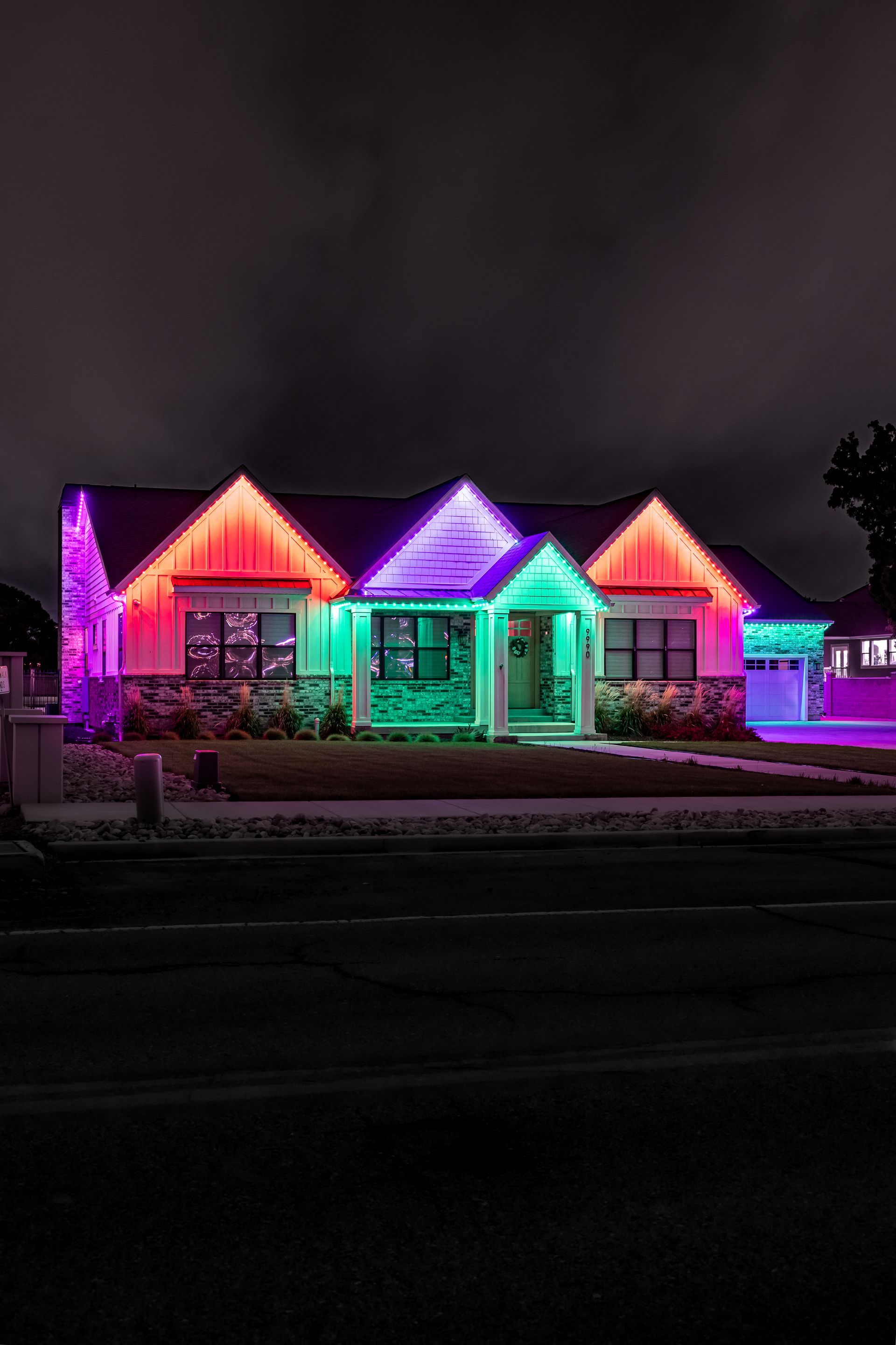 House at night illuminated with red, purple, and green lights.