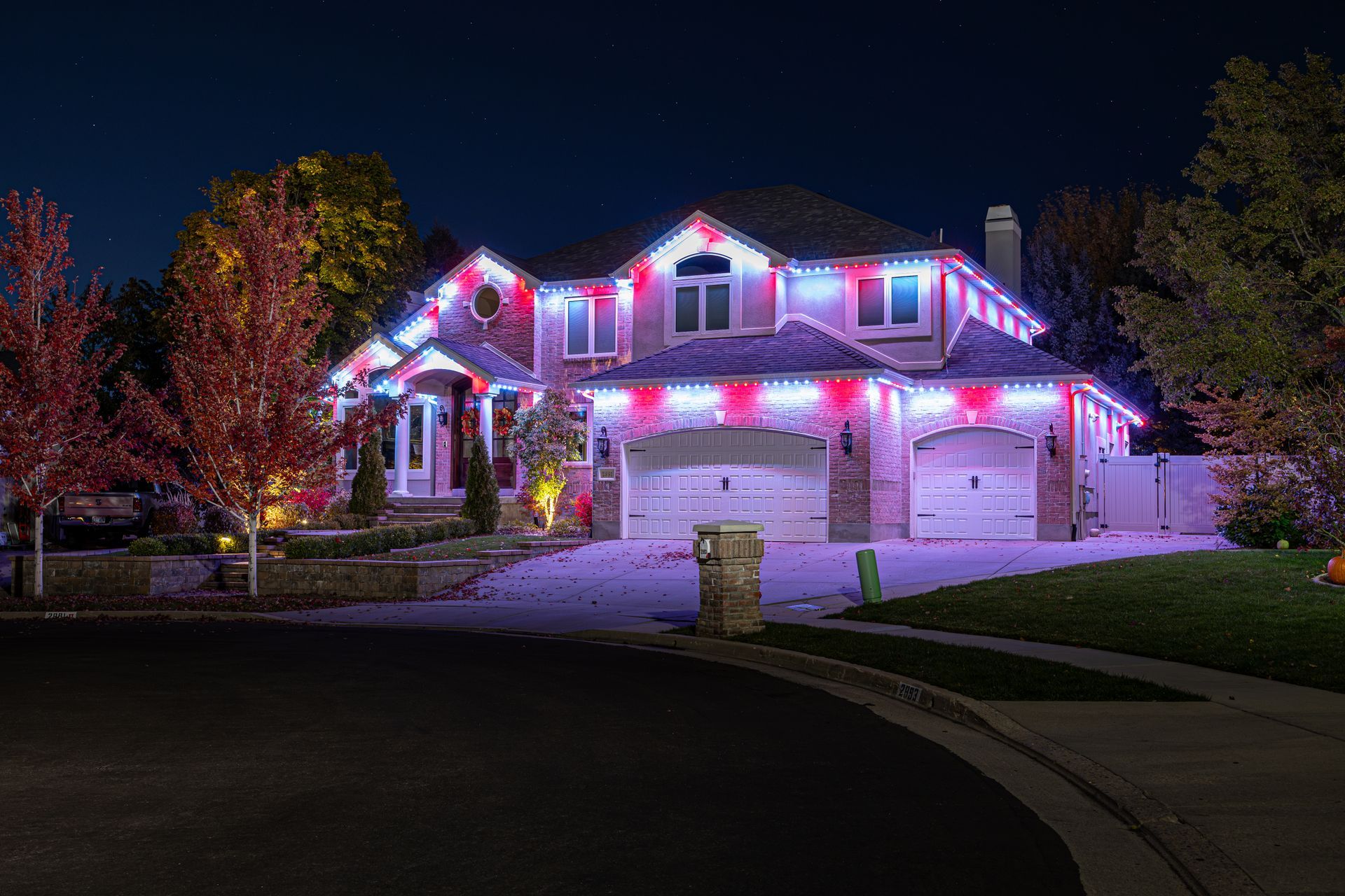 A house decorated with red, white, and blue Christmas lights at night.