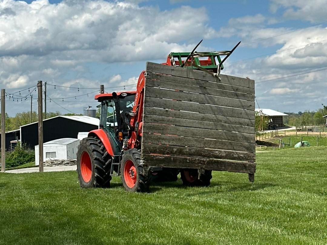 Orange Kubota tractor carrying an old barn door at Country Pumpkins in Dry Ridge, KY