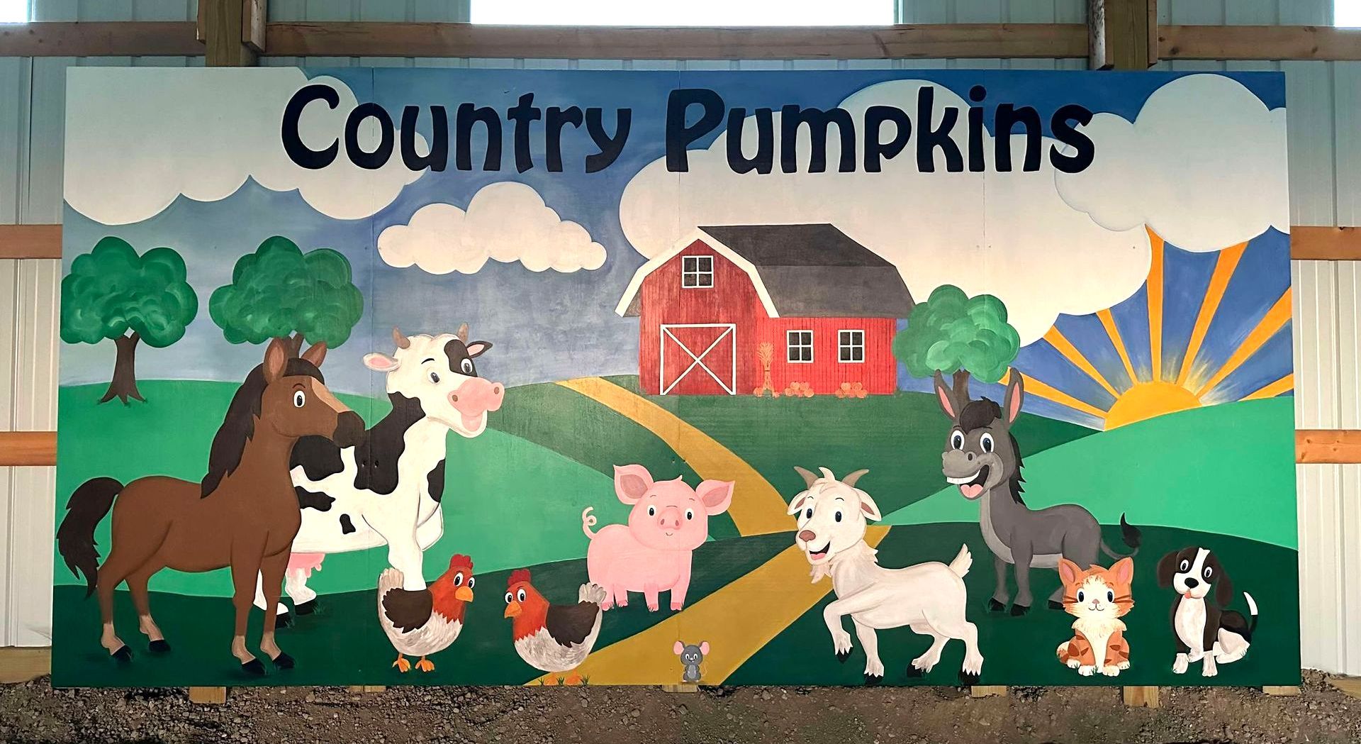 Large painted mural with a red barn, blue sky with white puffy clouds, and various cartoon farm animals at Country Pumpkins in Dry Ridge, KY.