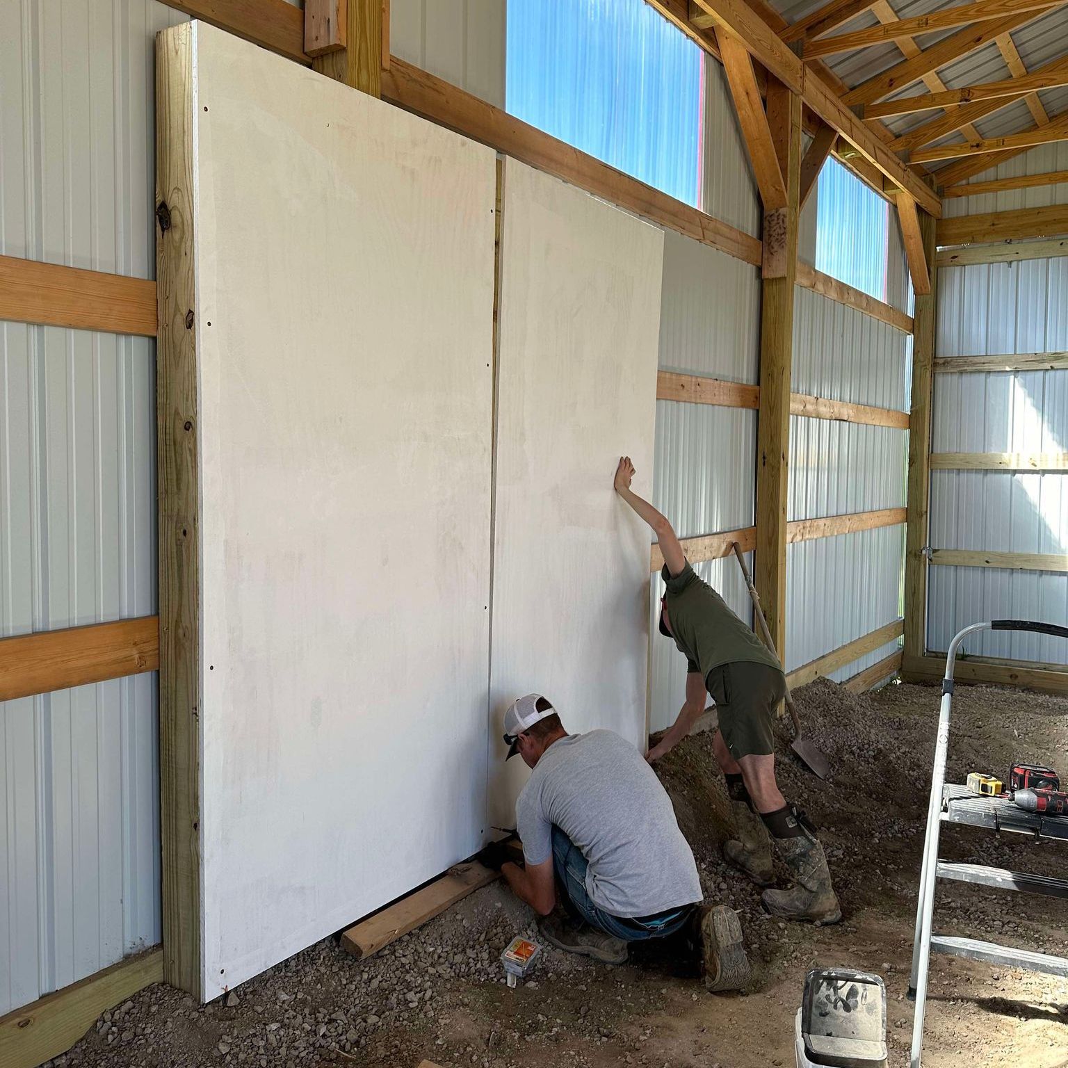 Two men screwing plywood to a barn wall to create a canvas for a mural at Country Pumpkins in Dry Ridge, KY.