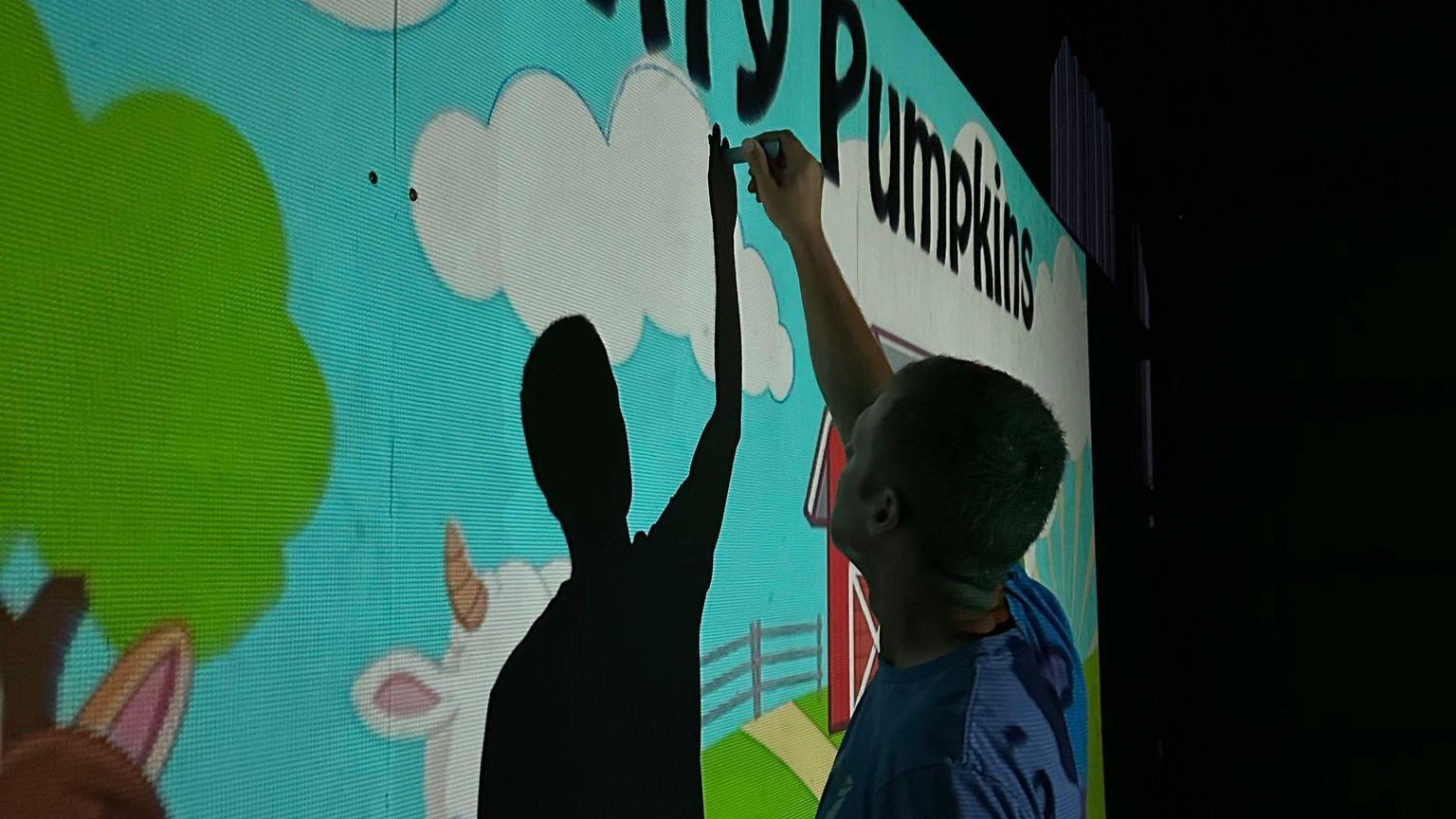 Man using chalk to trace a projected image onto wood at Country Pumpkins in Dry Ridge, KY.