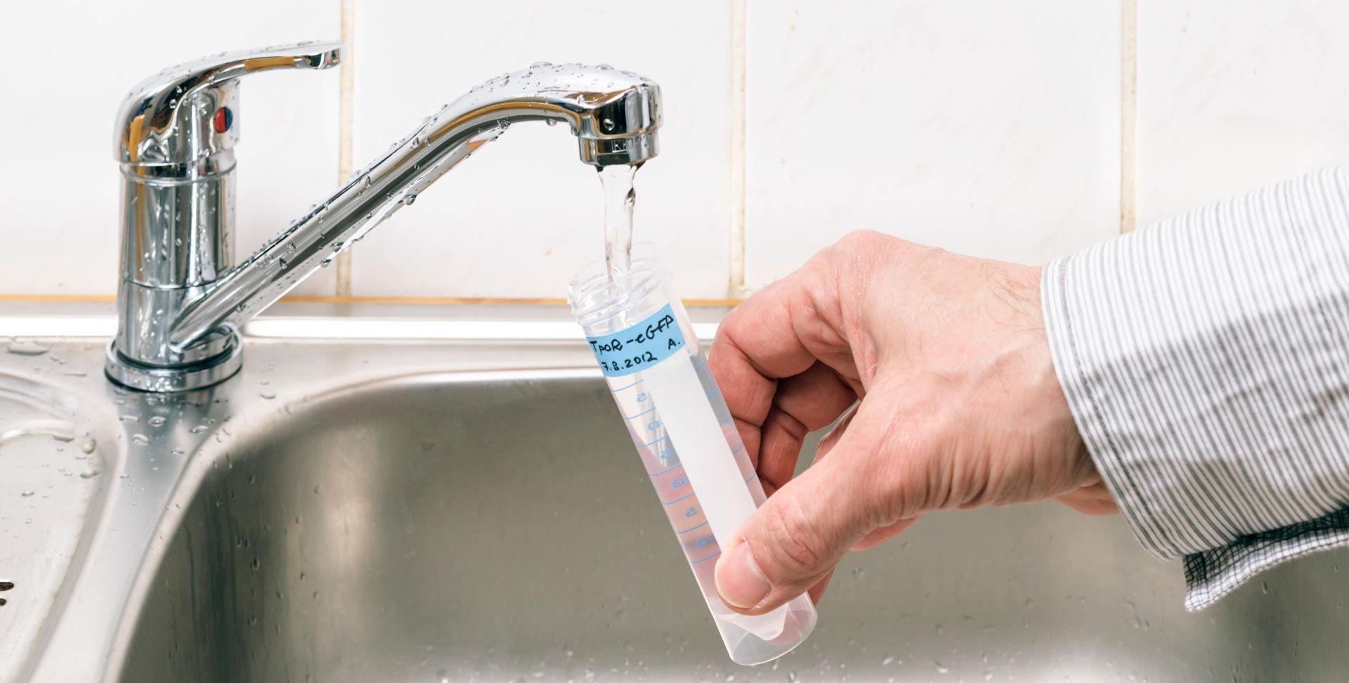 A person is washing a test tube in a sink.