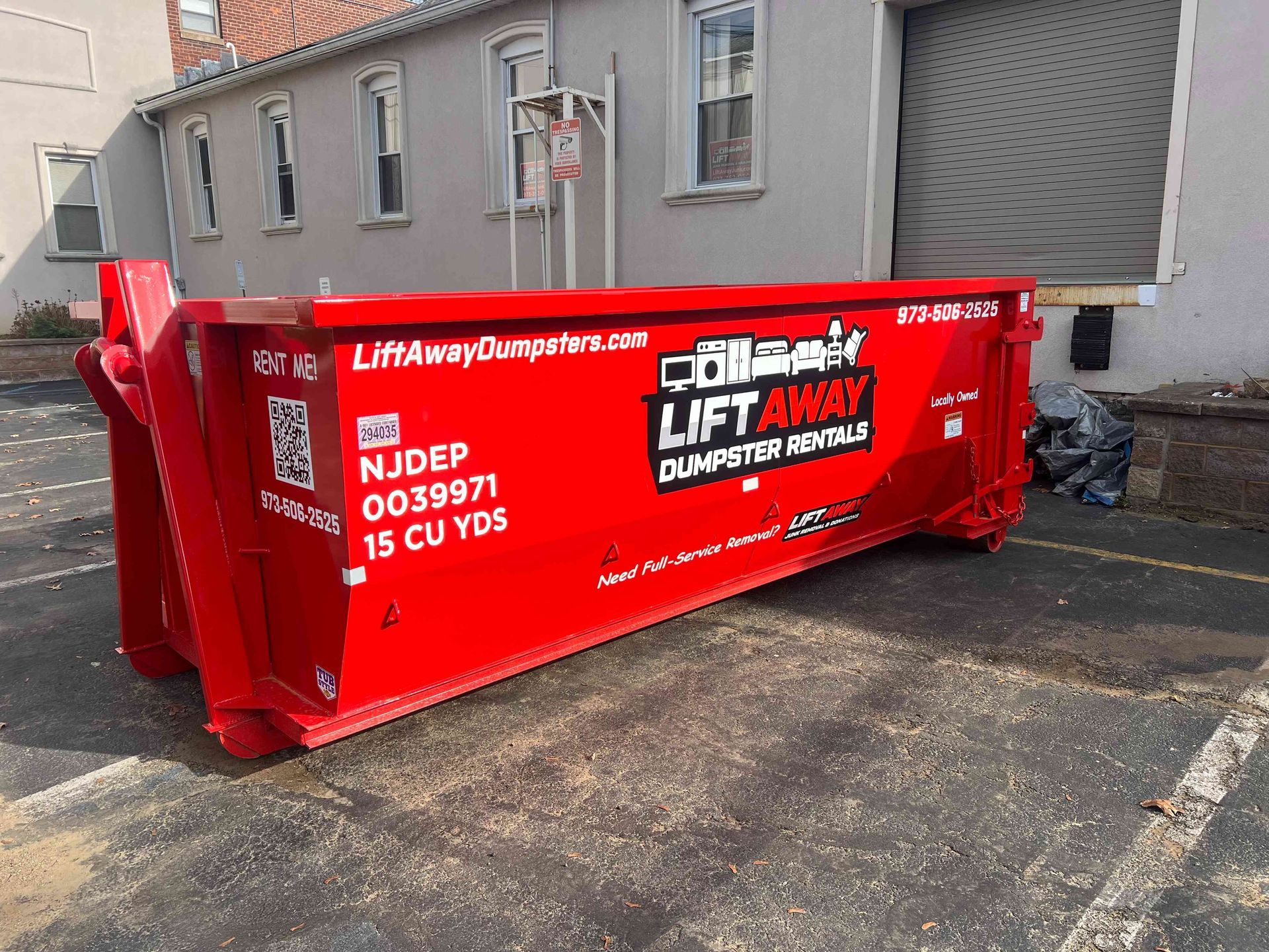 A group of movers in red hoodies and black pants are smiling while on the back of a truck.