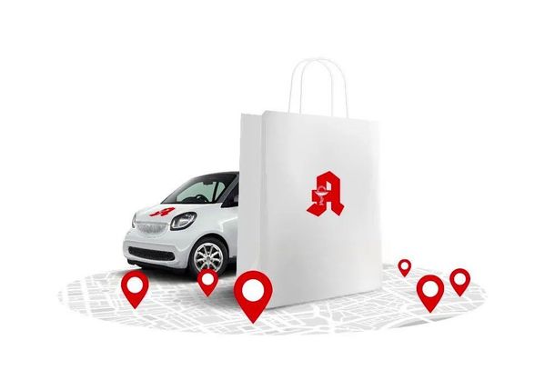 Weiße Apothekentasche mit rotem Logo neben einem kleinen Auto und roten Standortmarkierungen auf einer Karte.