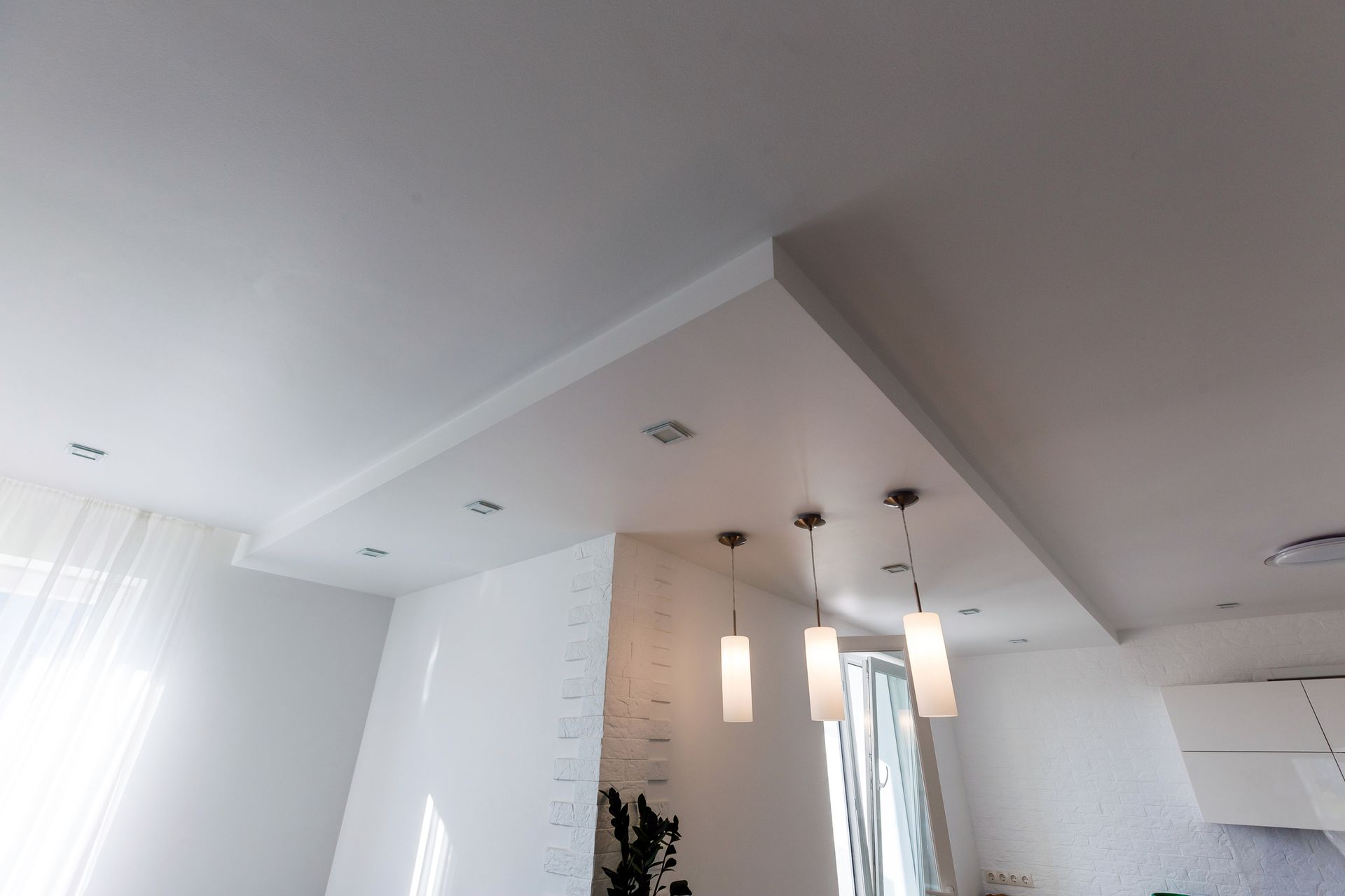 Un soffitto bianco da cui pendono alcune luci in un soggiorno.