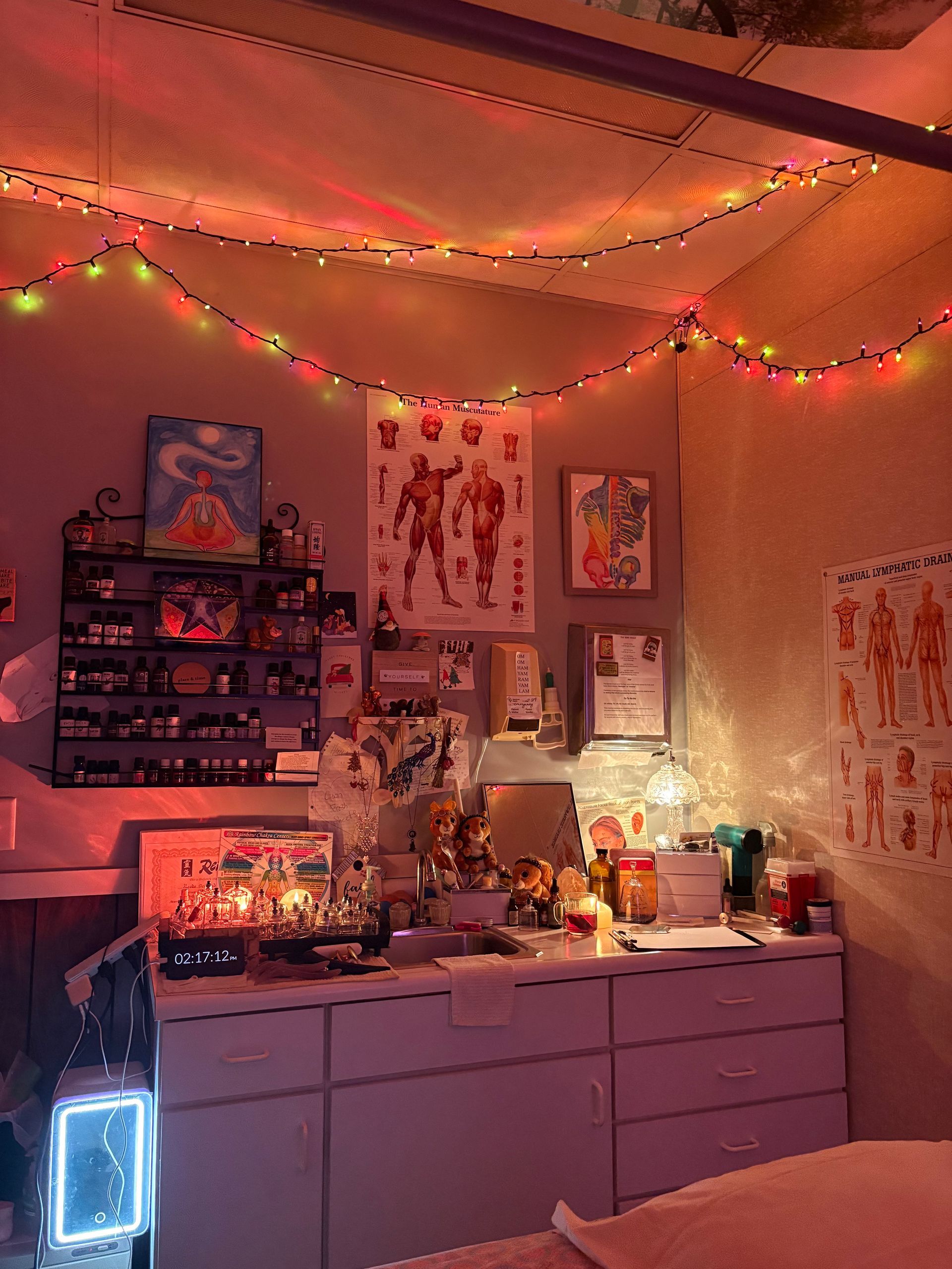 Cozy room lit by string lights. A dresser is cluttered with items, posters on the walls.