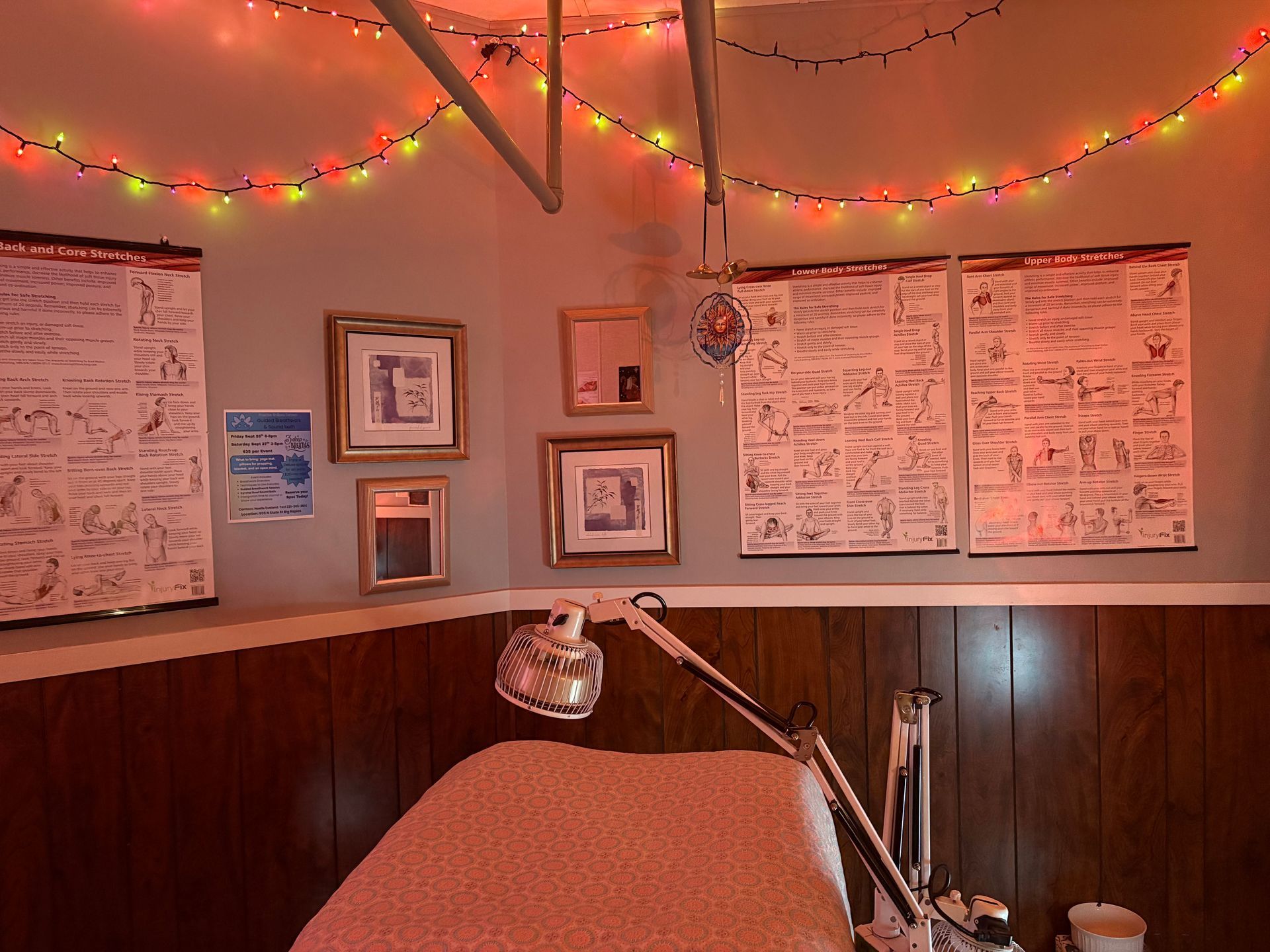 Cozy room with a bed, posters, framed pictures, string lights, and a lamp.