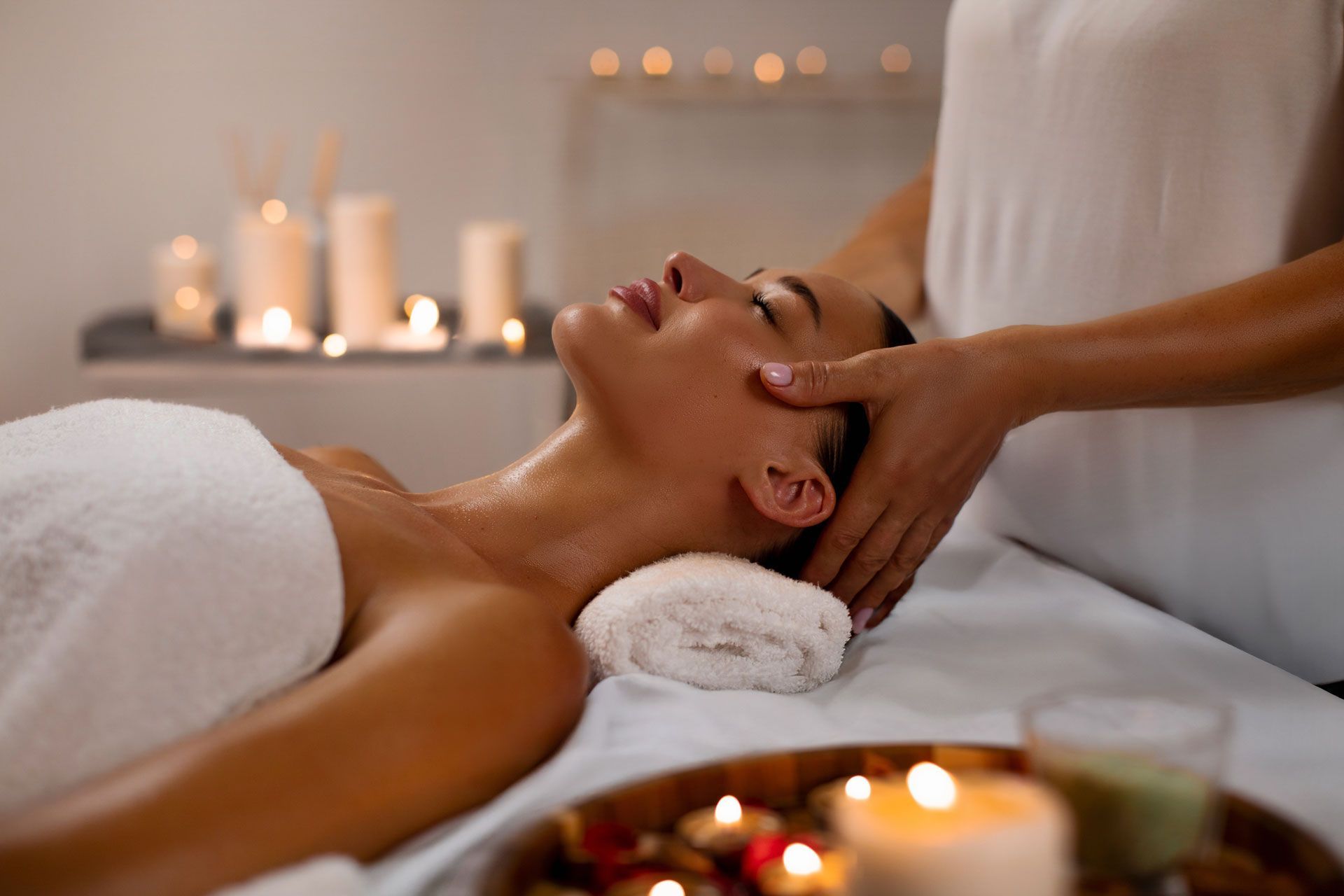 Woman receiving a back massage on a white massage table; hands pressing on her back.
