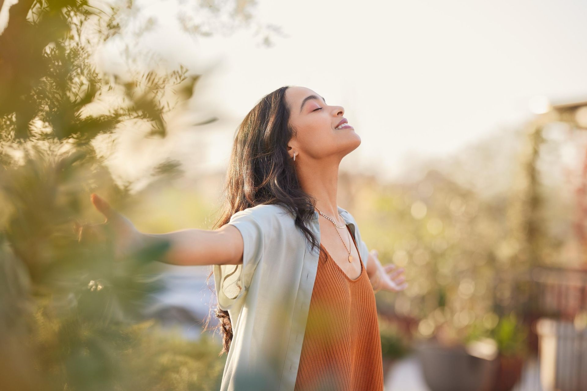 Woman with arms outstretched, eyes closed, basking in sunlight.