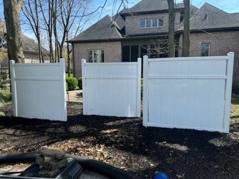 Three white fences are sitting in front of a house.