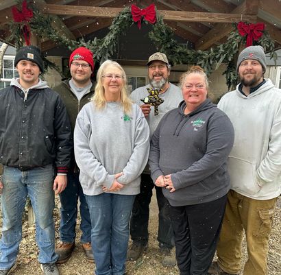 The Rustic Pines Tree Farm crew posing for a picture in front of the craft shop decorated for Christmas