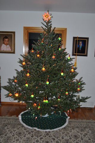 A Christmas tree in a living room with a green skirt