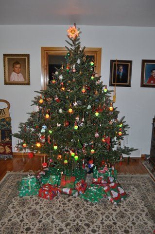 A christmas tree in a living room with gifts underneath it.