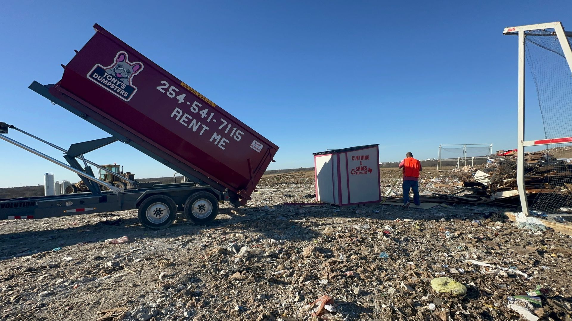 A green dumpster is sitting in front of a house under construction.