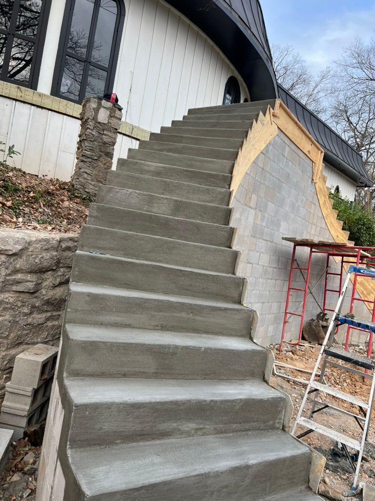Newly constructed concrete staircase leading to a building's entrance. Adjacent wall under construction.