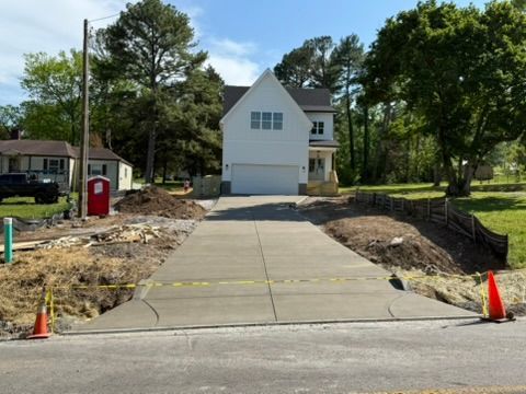 New concrete driveway leading to a white two-story house under construction.