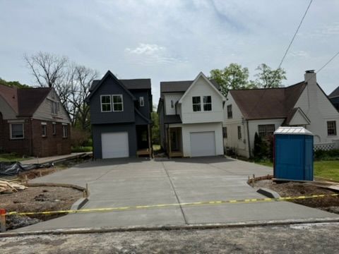 Two new houses under construction with newly poured concrete driveways. 