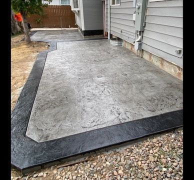 Stamped concrete patio with a dark border. Grey-toned interior with textured finish. Adjacent to a house.