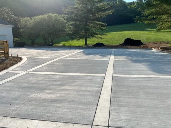 Newly poured concrete driveway with grid pattern and surrounding green grass.