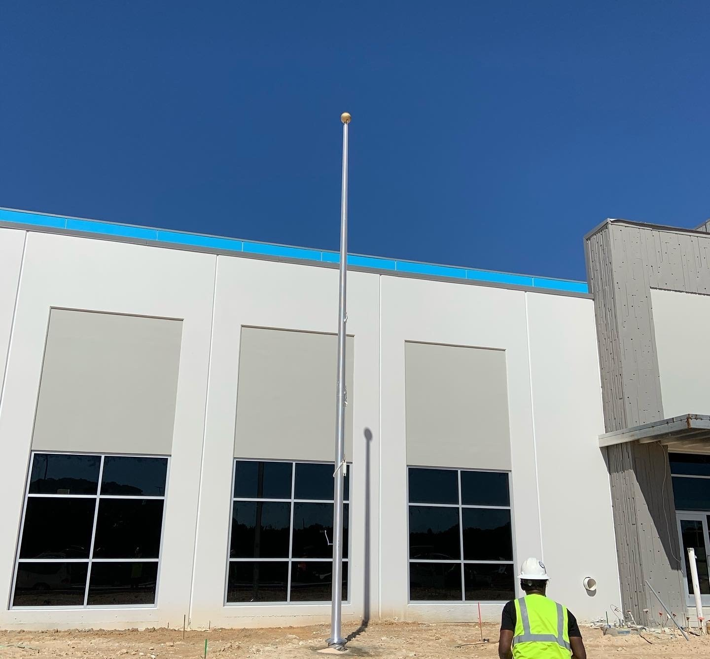 A man in a hard hat is standing in front of a building under construction.