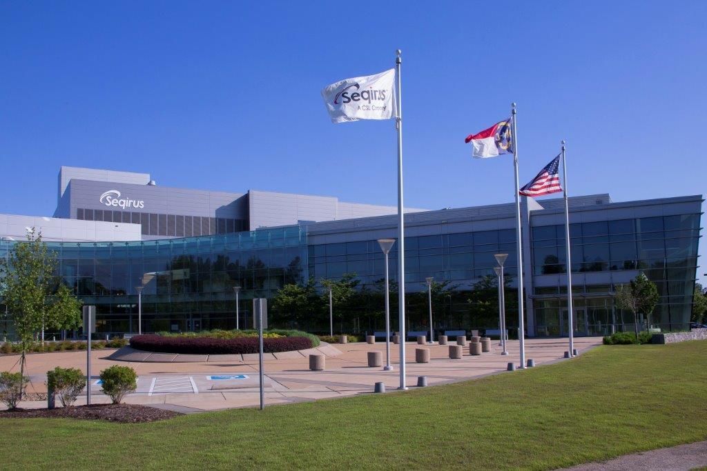 Several flags are flying in front of a large building