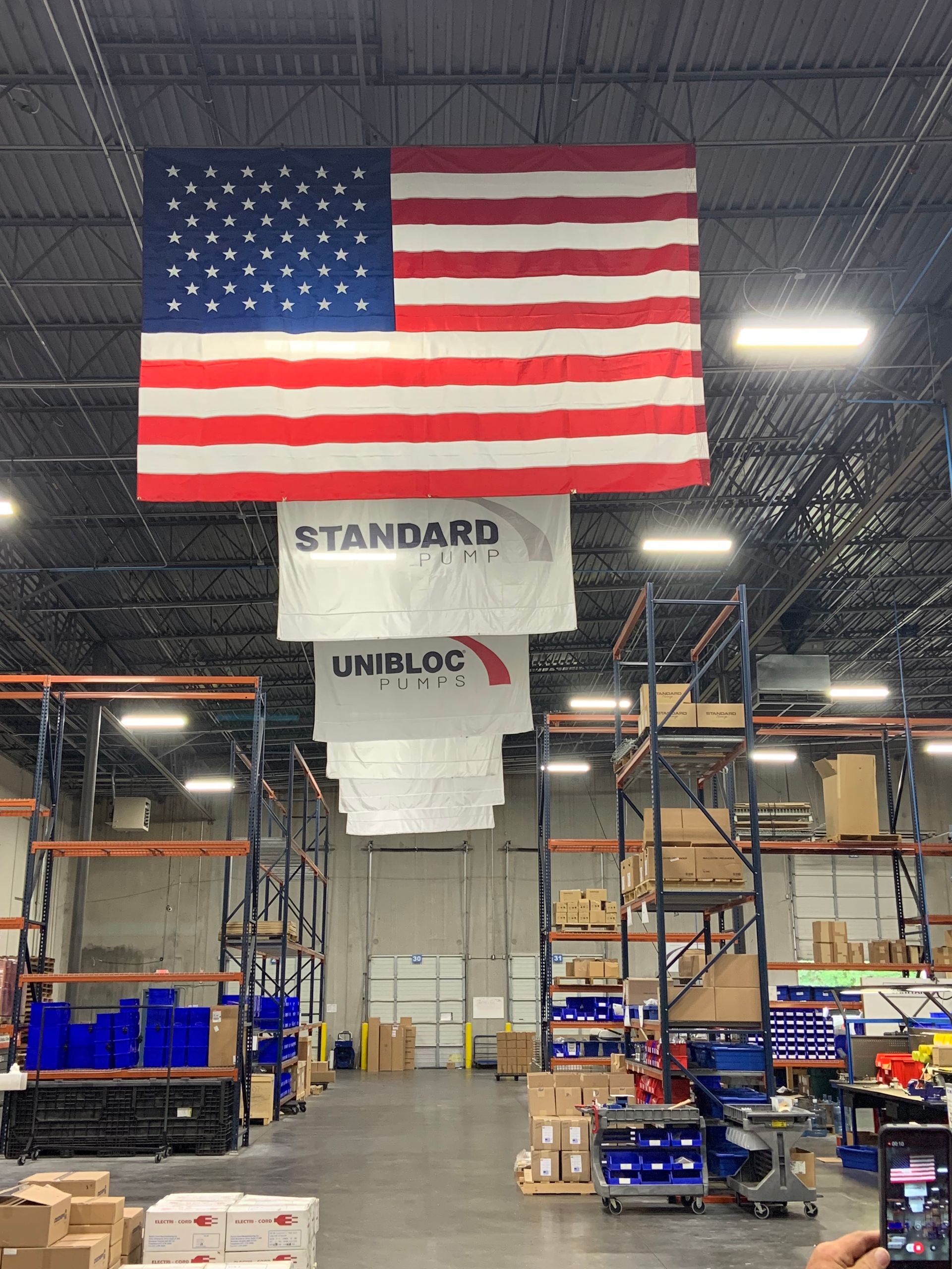 Large US and Custom Flags Hanging  Inside of an Industrial Building