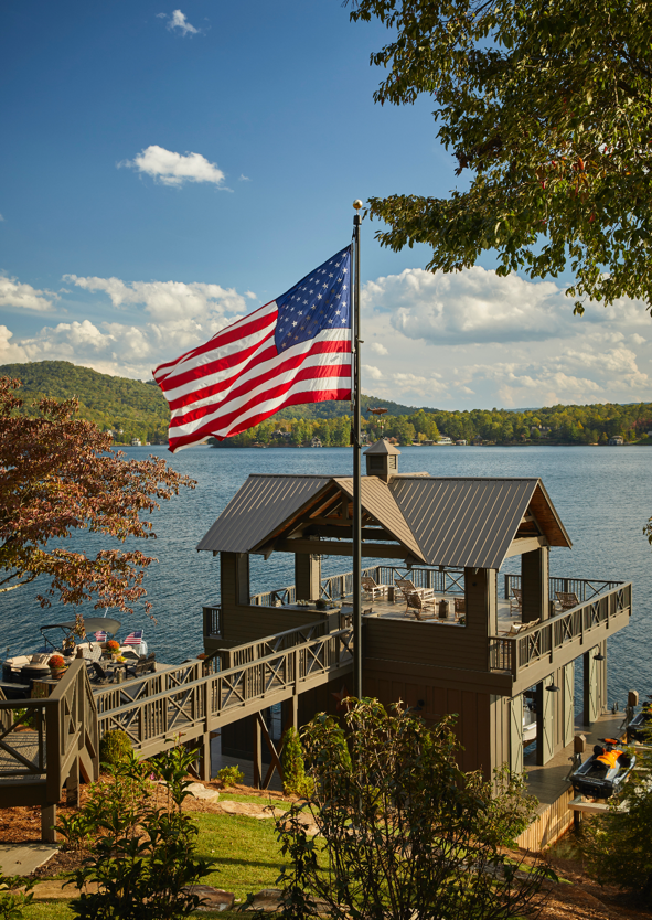 An American flag is flying in front of a dock and lake