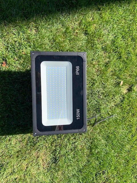 A flood light is sitting on top of a lush green field.