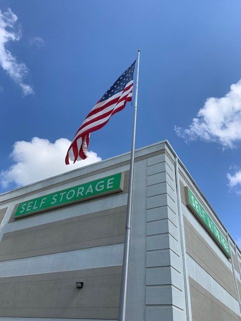 An american flag is flying in front of a self storage building