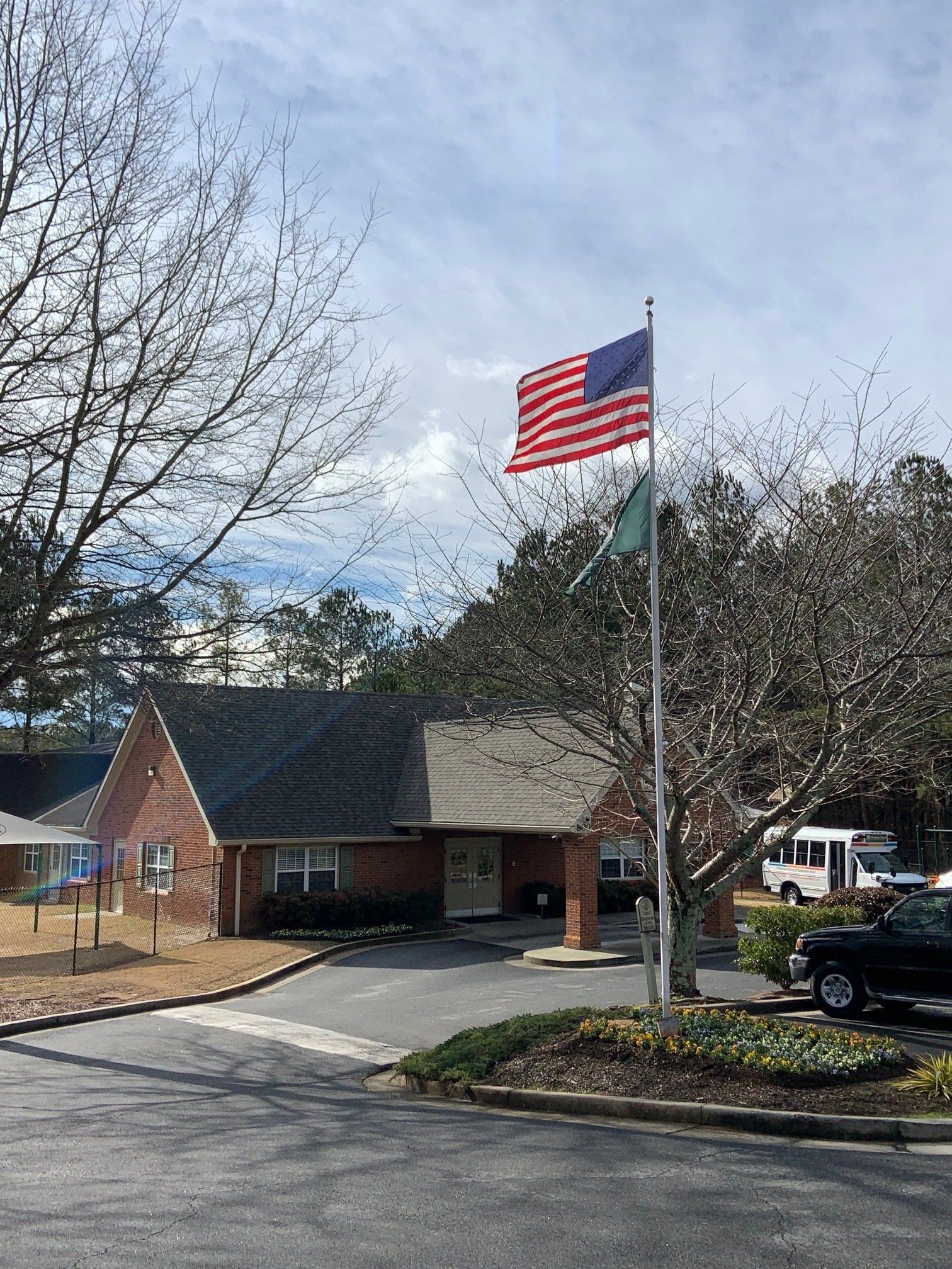 An american flag is flying in front of a brick building.