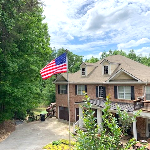 An american flag is flying in front of a large brick house
