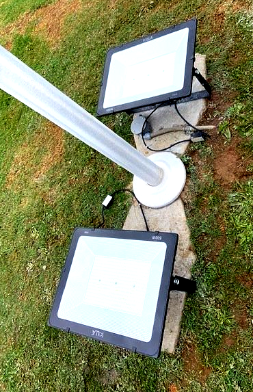 Two square lights are sitting on top of a concrete block in the grass.