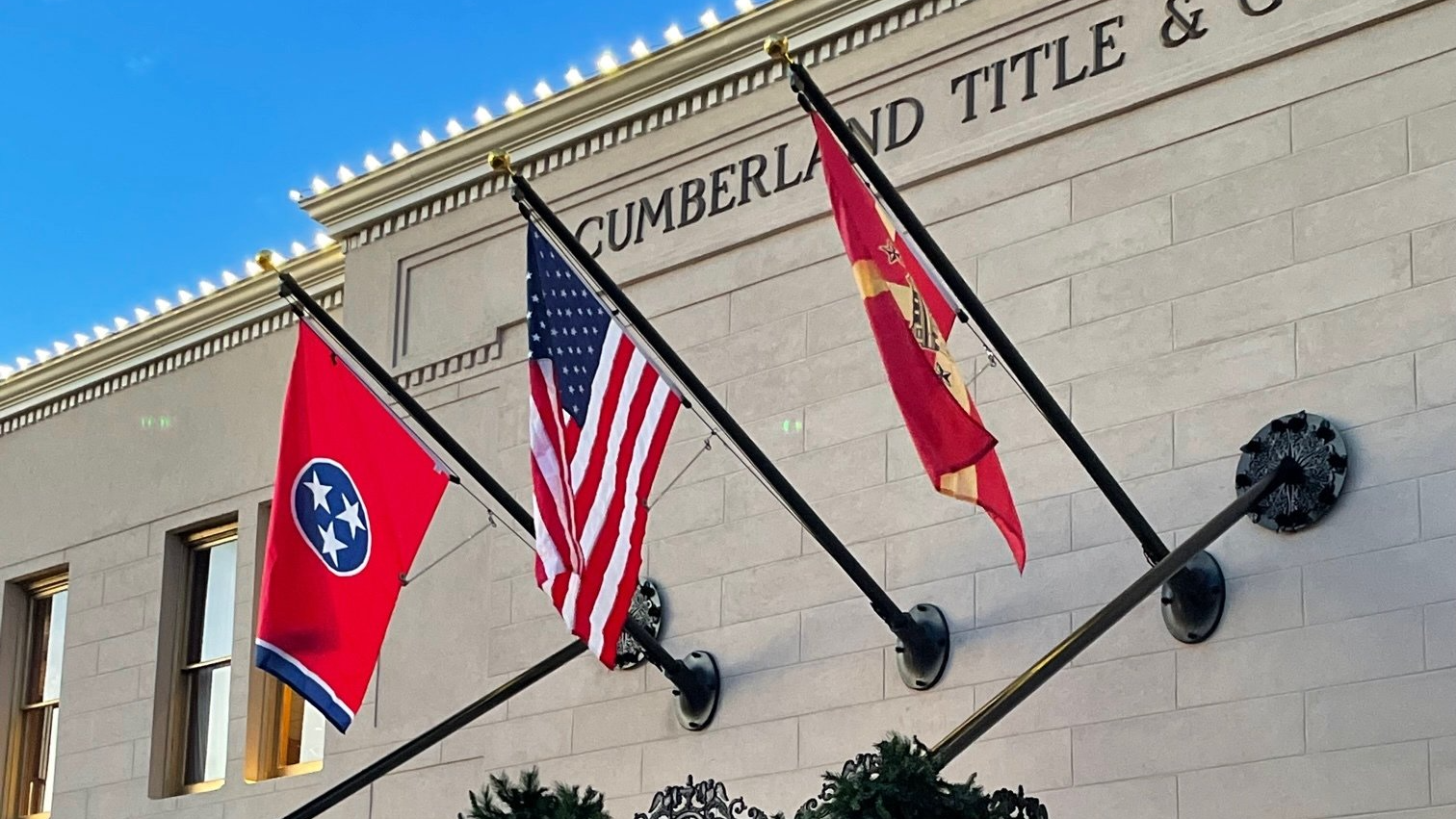 Four flags are flying in front of a building that says cumberland and title