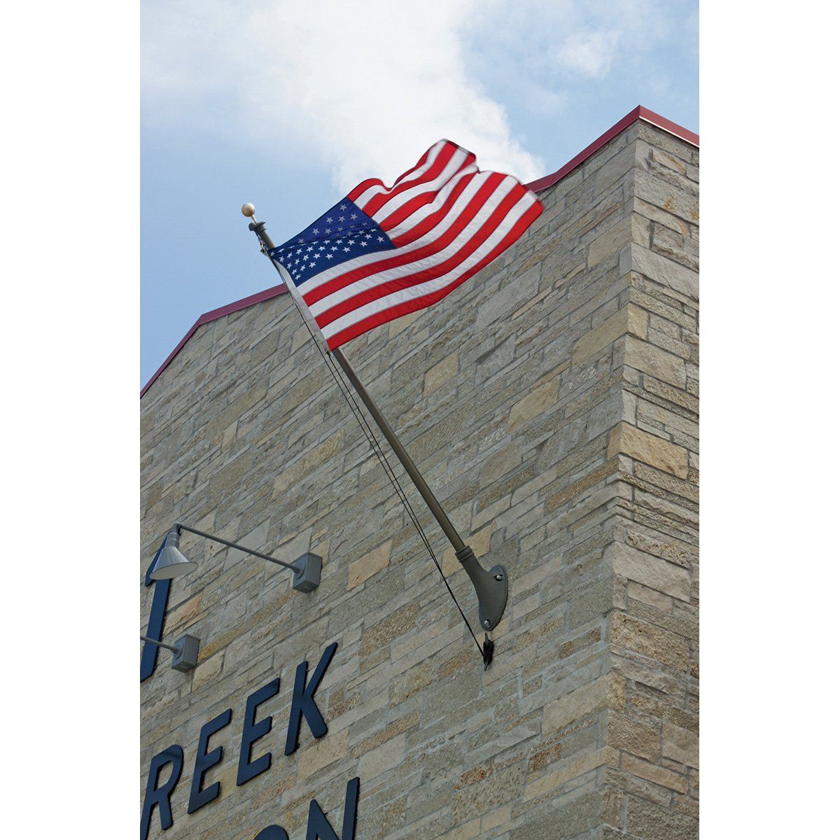 An american flag is flying on the side of a building that says reek