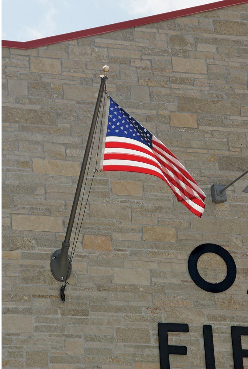 An american flag is hanging from a pole on the side of a building