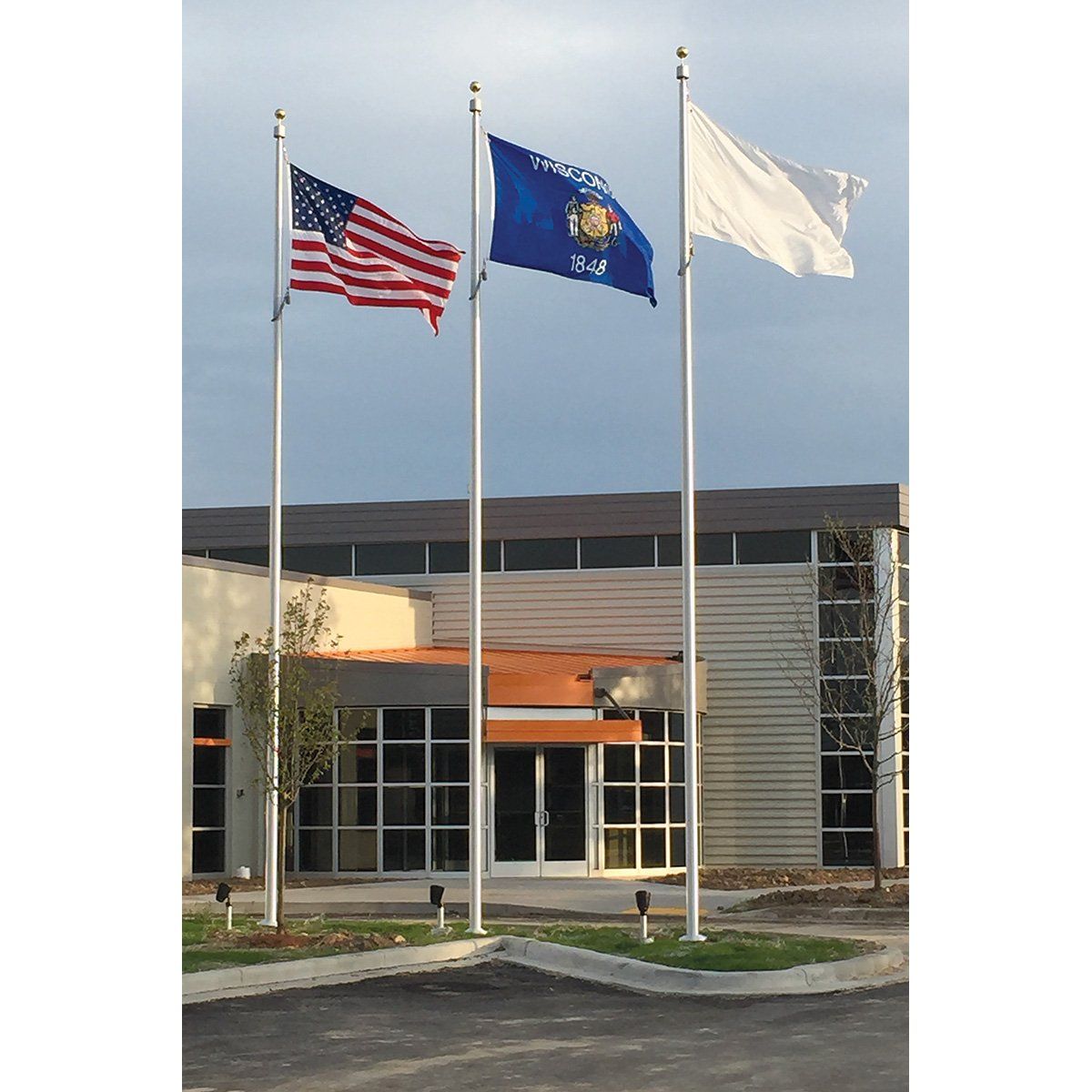 Three flags are flying in front of a building