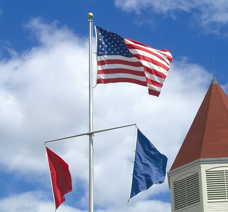 An american flag and a red and blue flag on a pole