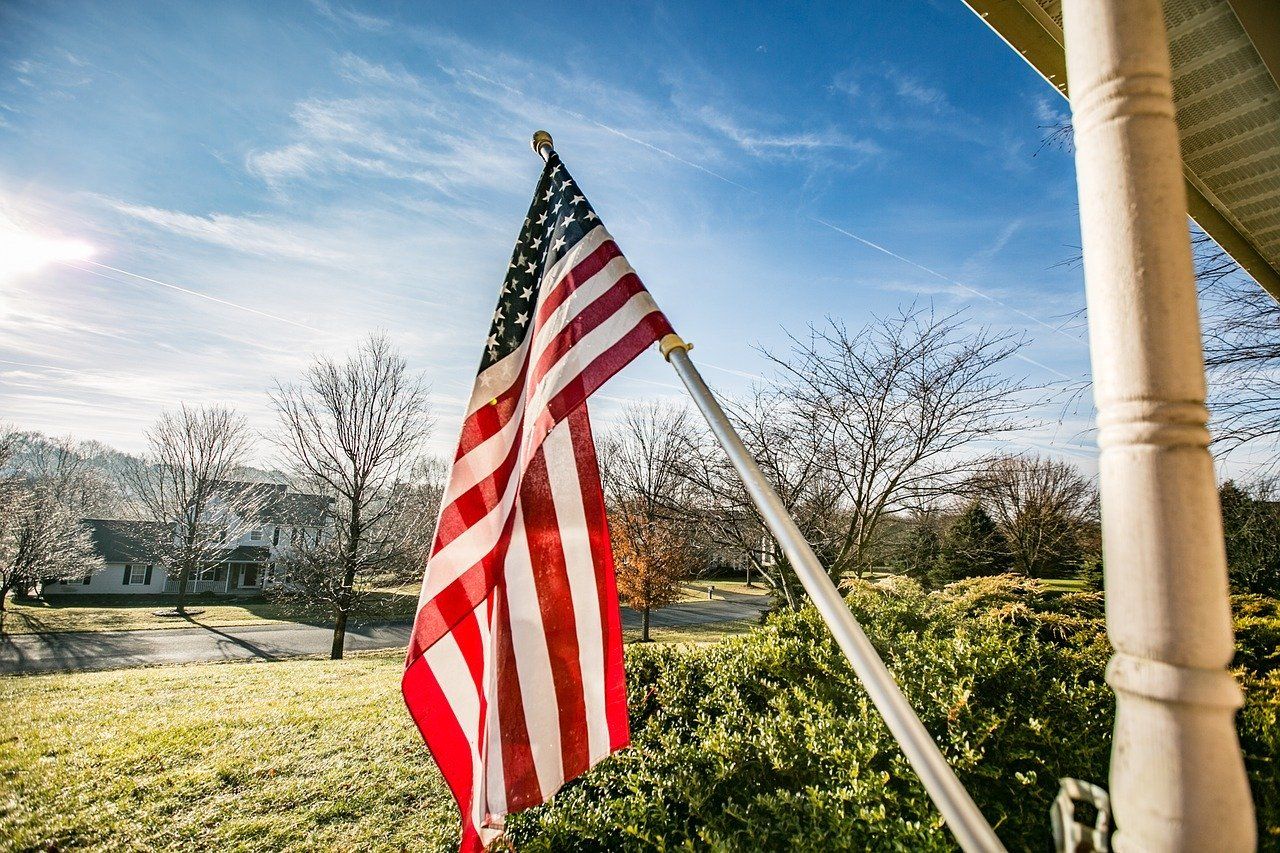 An american flag is flying on a pole in front of a house.