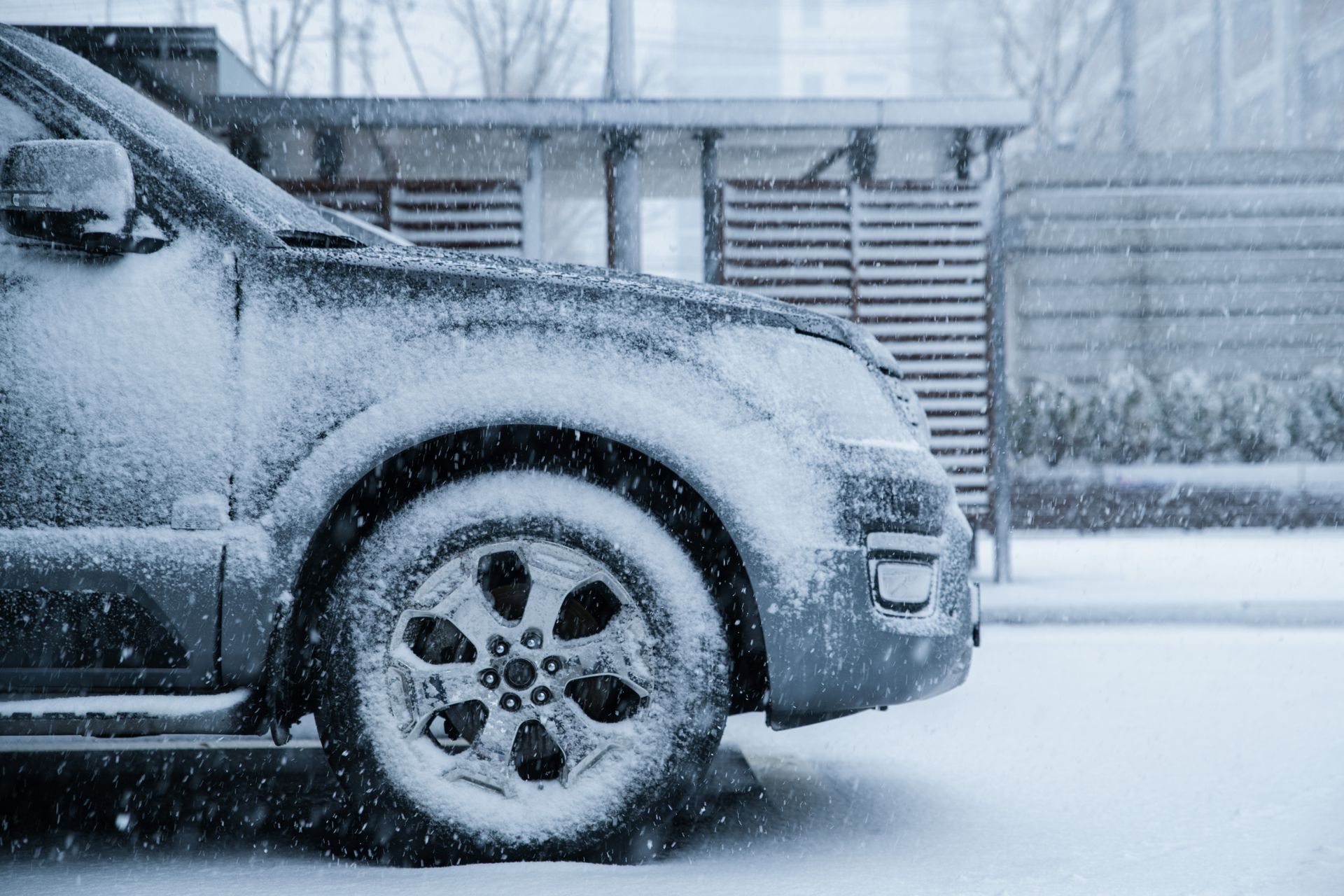Car covered in snow parked outdoors during a winter storm.