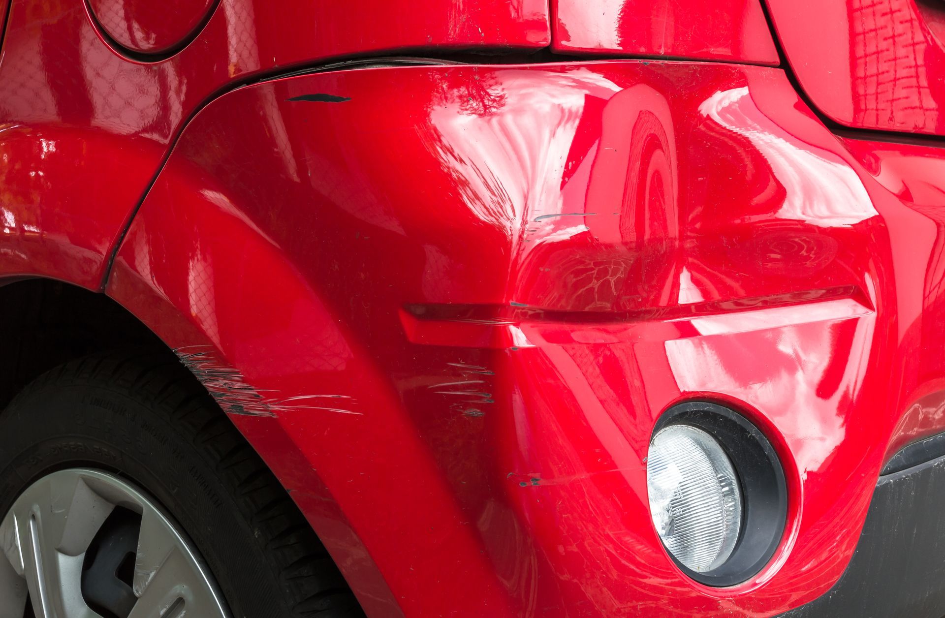 Red car bumper with scratches and a dent.