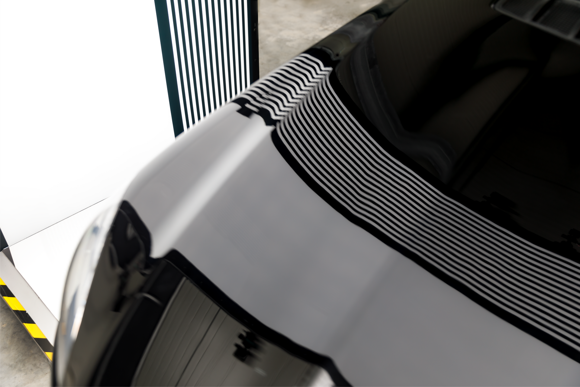 Black car hood reflecting a lined pattern used for assessing the surface.