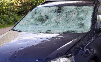 a car with a broken windshield is parked on the side of the road