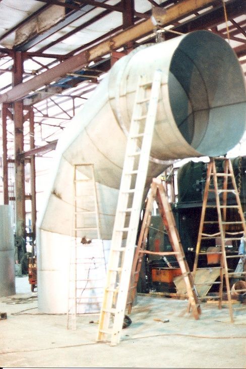 A large metal pipe is being built in a factory