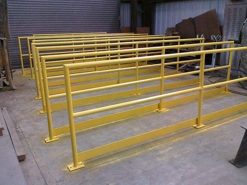 A row of yellow metal railings sitting on top of a concrete floor.